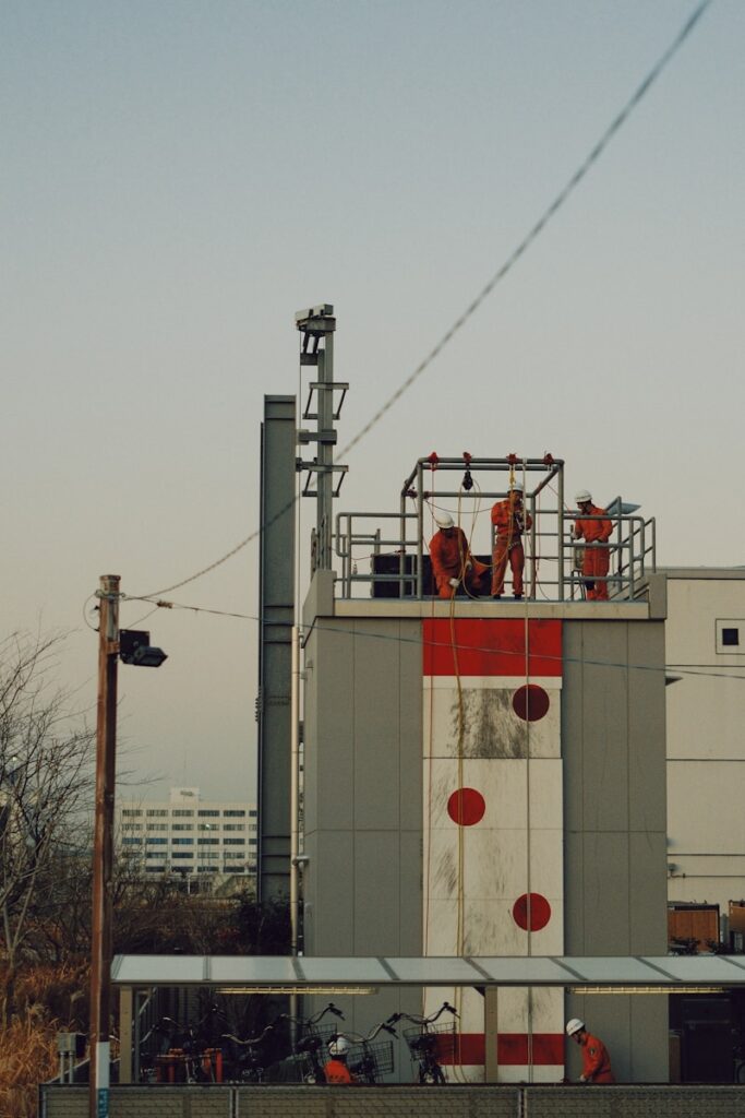 Workers in orange suits on a tall industrial structure
