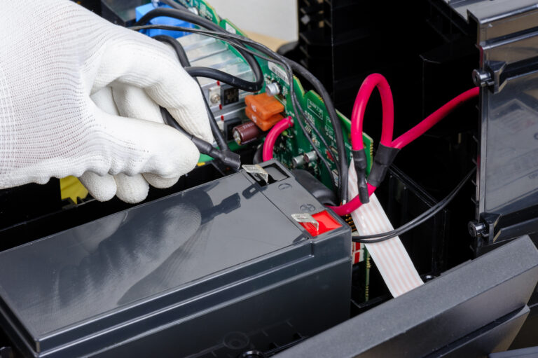 Technician servicing UPS battery components during backup power replacement and maintenance.